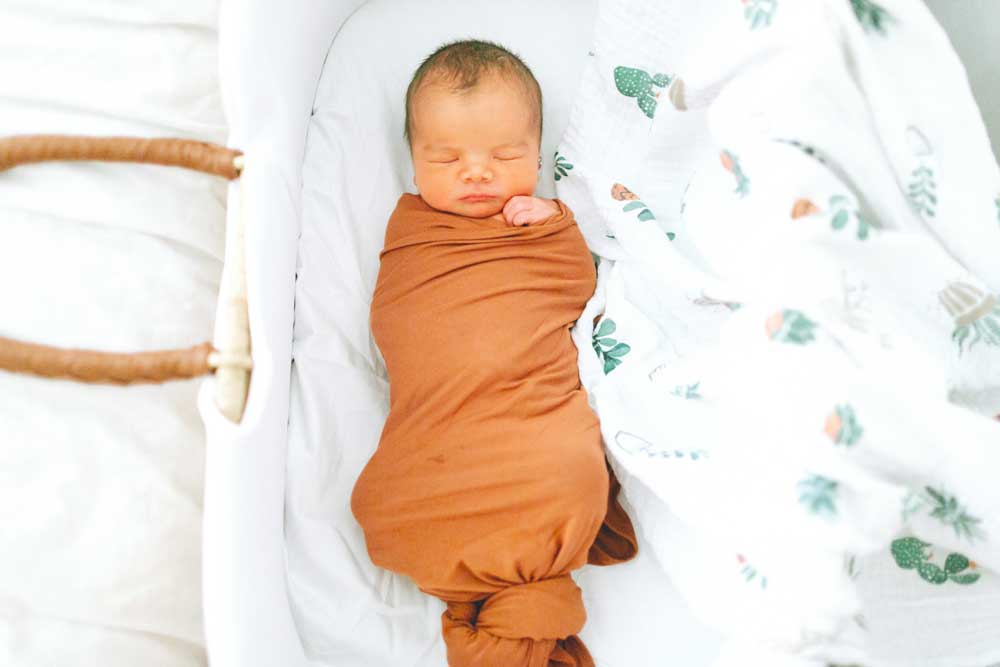 baby wrapped in a brown swaddle blanket
