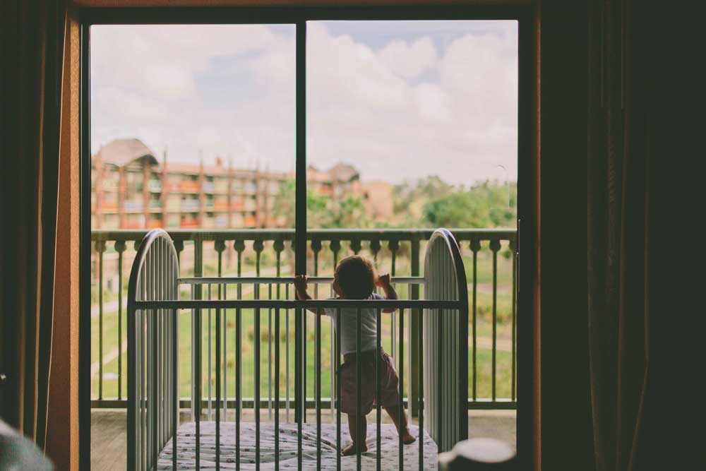 baby in her crib looking outside through a glass