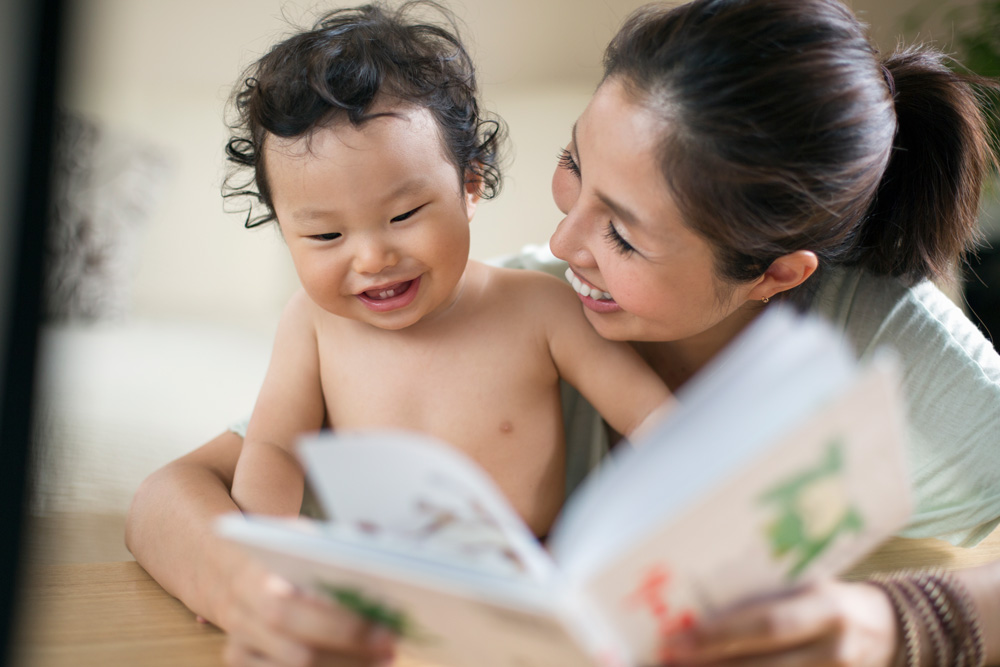 mother and baby laughing while reading a book