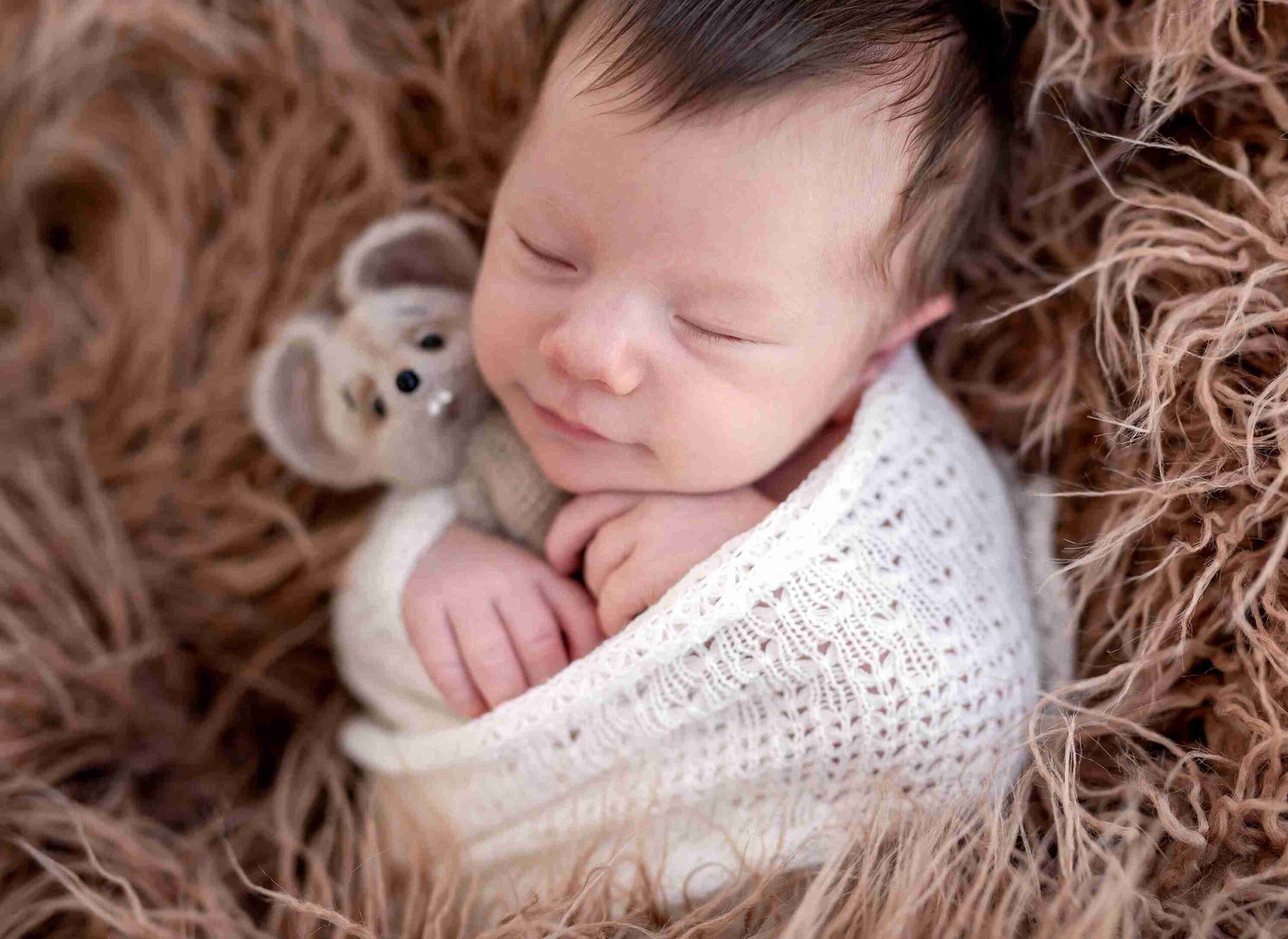 baby sound asleep embracing a stuffed toy