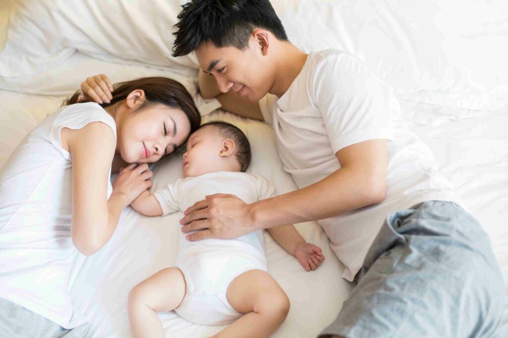 parents lying in bed with their baby between them